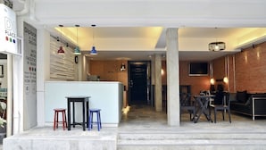 Un interior moderno con una zona de bar, asientos y una escalera que lleva a un altillo.