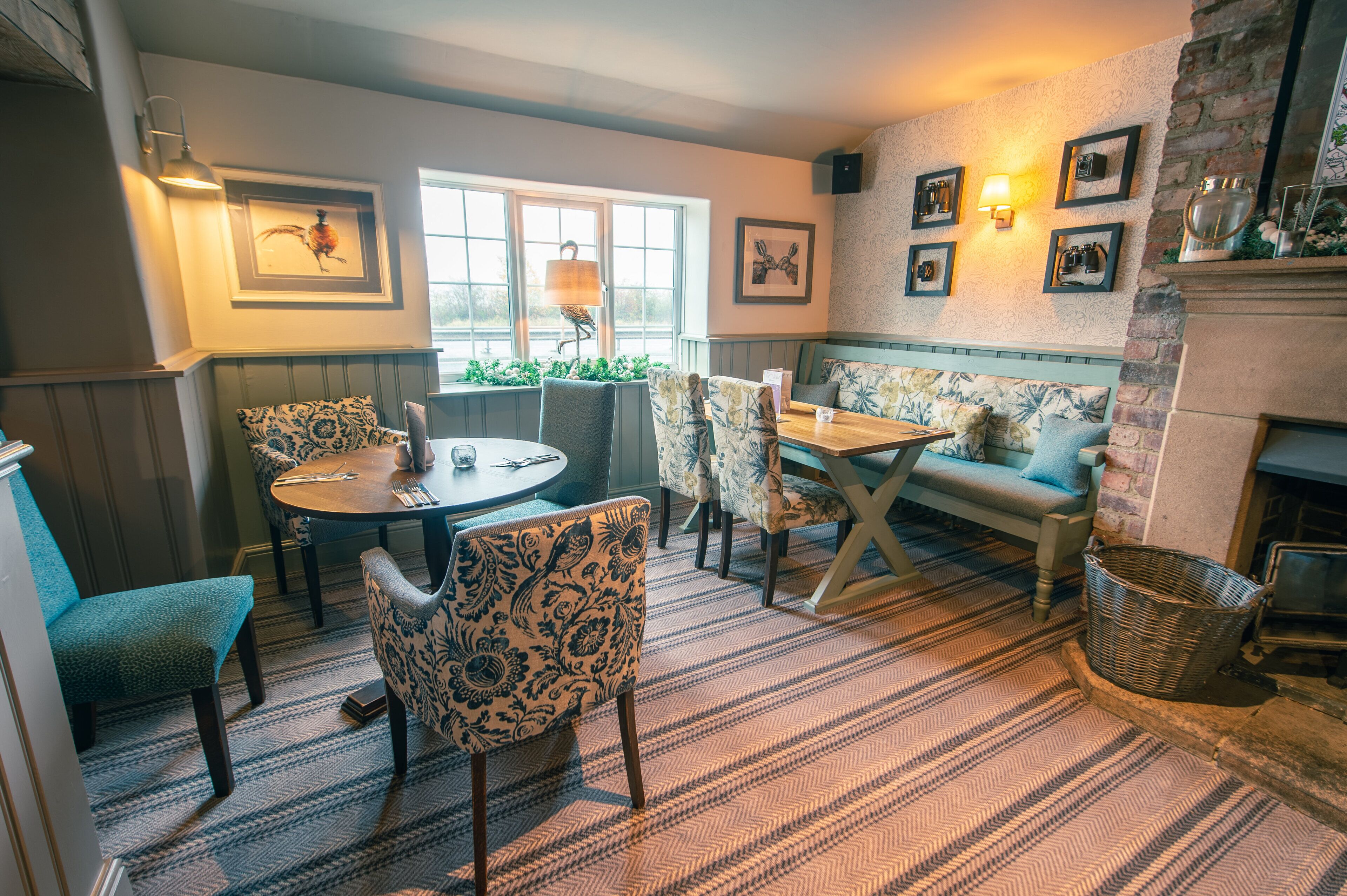 A cozy room with a round table, patterned chairs, a sofa, and a fireplace.