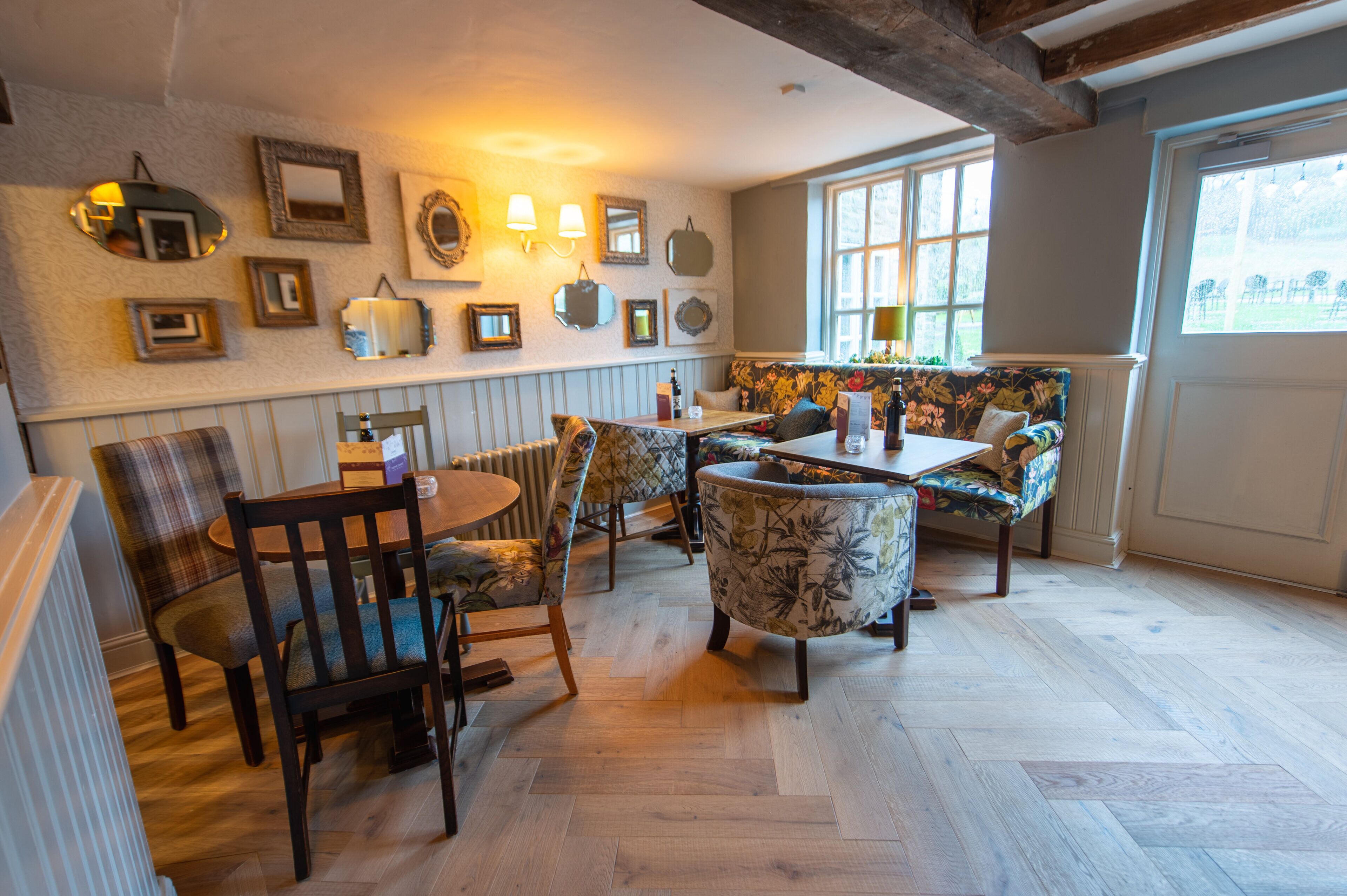 A cozy dining area with wooden furniture, a patterned sofa, and wall-mounted lights.
