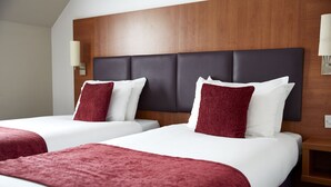 Two beds with red and white bedding, a wooden headboard, and a nightstand with a lamp. - Cross Keys Hotel by Chef and Brewer Collection (Guisborough)
