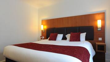 Ein Hotelzimmer mit einem großen Bett, einem Holzkopfende, zwei Nachttischen und Wandlampen.