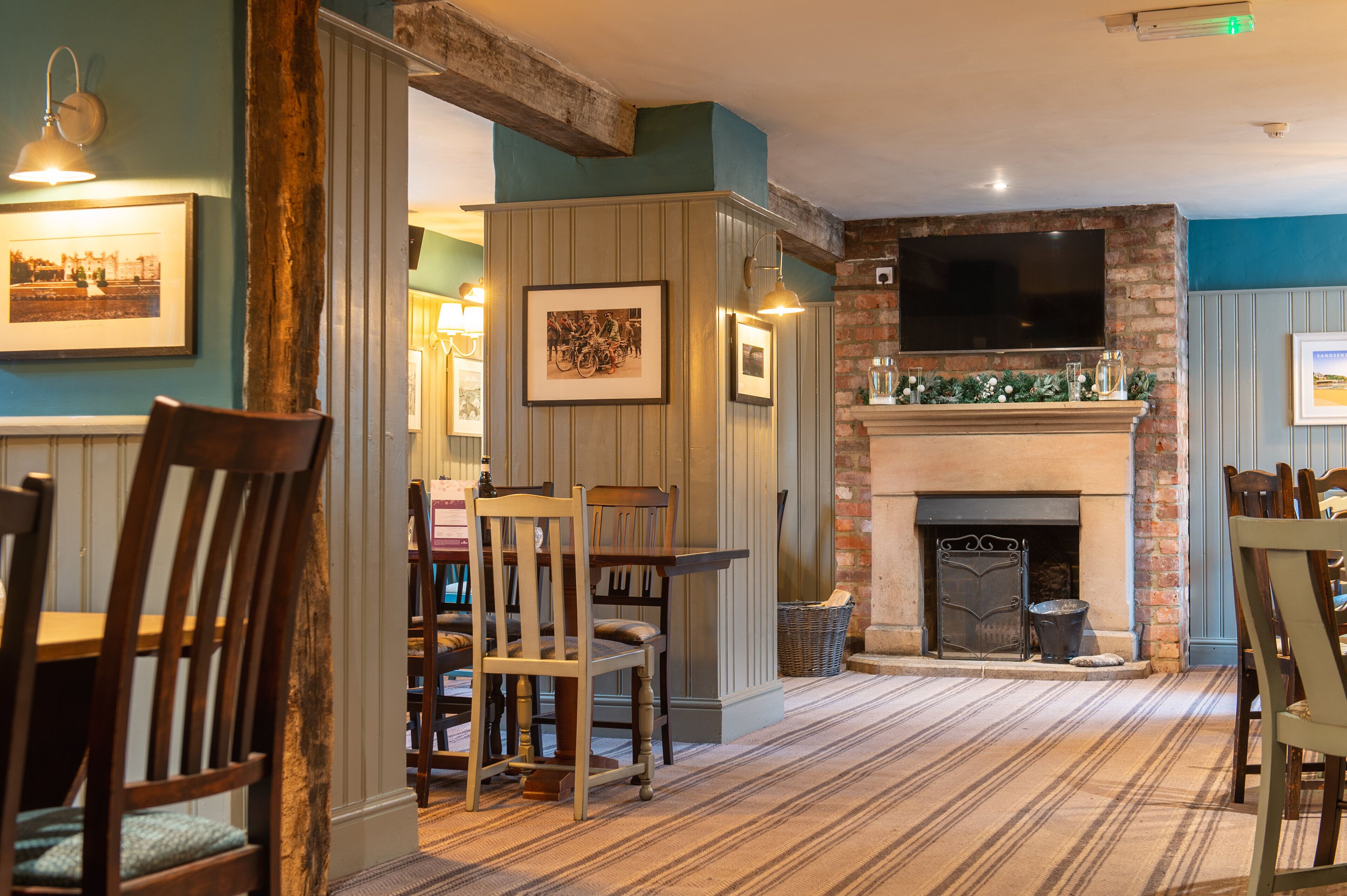A dining area with wooden chairs, a fireplace, and framed pictures on the walls.