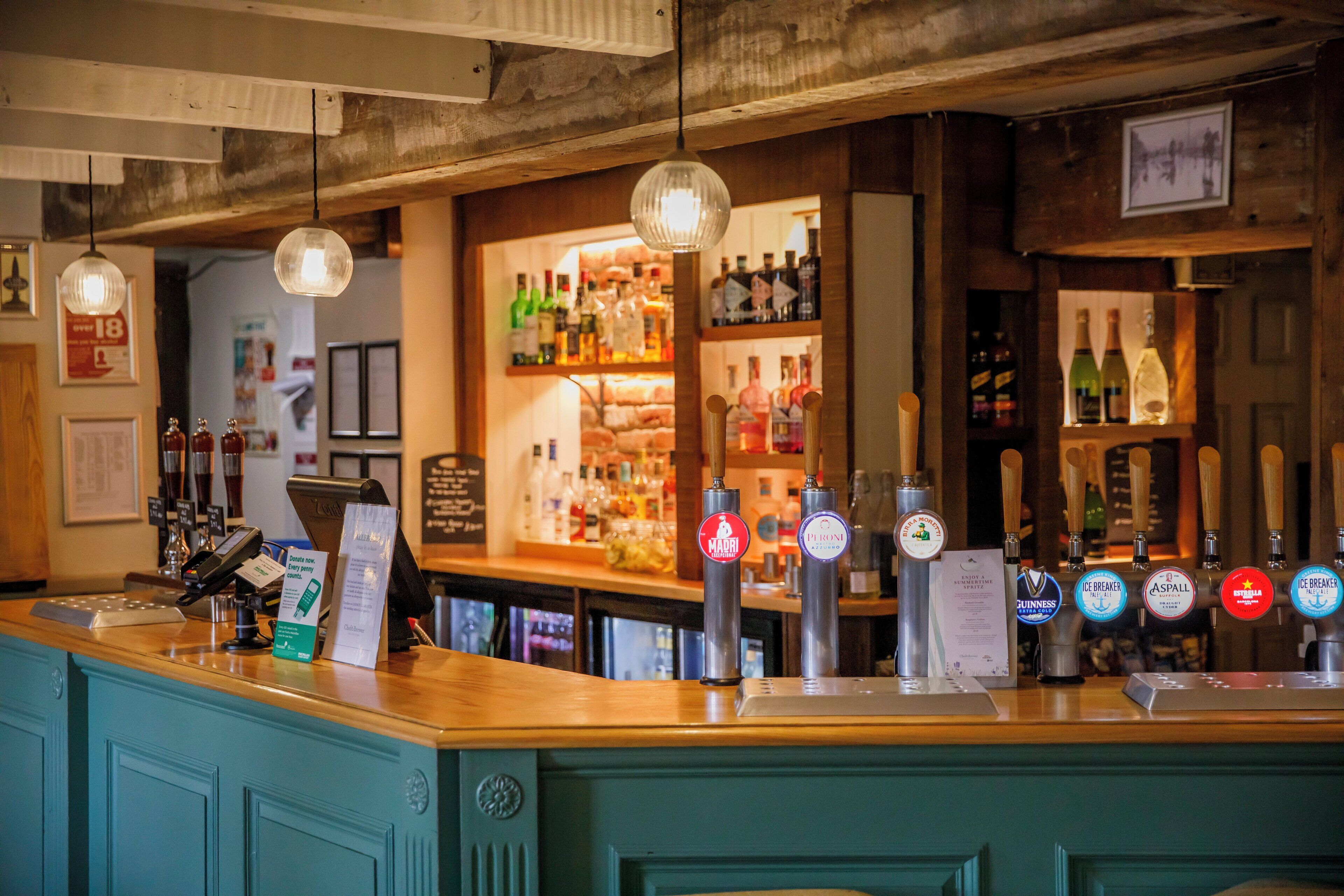 Eine Bar mit einer Theke, mehreren Zapfhähnen und einer Auswahl an Spirituosenflaschen.