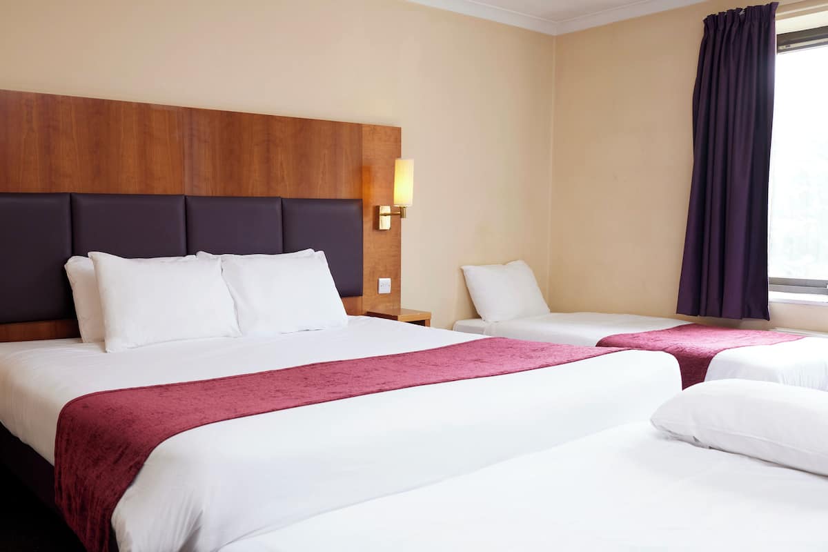 Ett hotellrum med två sängar, trägavlar och väggmonterade lampor.