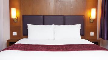 A hotel room with a large bed, two nightstands, and wall-mounted lamps.