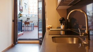 A modern kitchen with a stainless steel sink, a built-in oven, and a window overlooking a balcony. - Casa Felipa Plaza España (Barcelona)