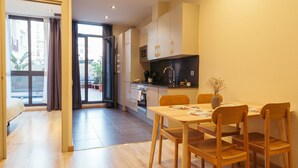 A modern kitchen with wooden cabinets, a dining table with chairs, and a view of the outside through a sliding door. - Casa Felipa Plaza España (Barcelona)