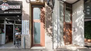 A sushi bar restaurant with a glass door entrance, a menu board outside, and a small outdoor seating area. - Casa Felipa Plaza España (Barcelona)