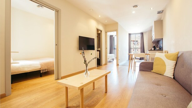 A modern living room with a sofa, a coffee table, and a TV mounted on the wall. - Casa Felipa Plaza España (Barcelona)