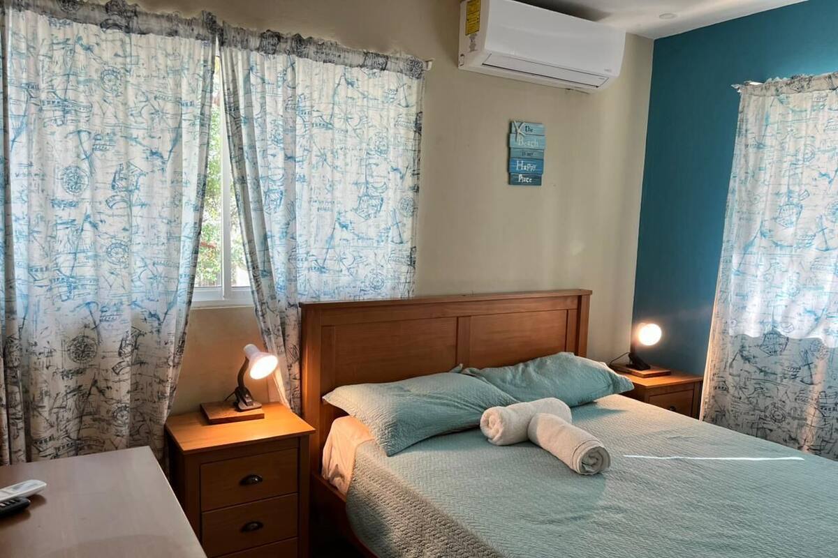 Ein Schlafzimmer mit Bett, Nachttischen, einer Lampe und Vorhängen.