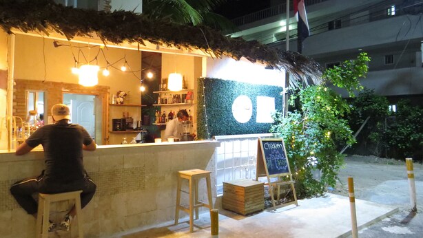 A restaurant with a thatched roof, a counter, and a signboard. - Punta Cana Hostel (Punta Cana)