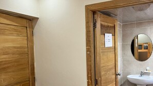 A bathroom with a wooden door, a white sink, and a mirror. - Punta Cana Hostel (Punta Cana)