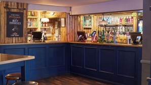 A bar area with wooden paneling, a counter with a cash register, and stools.