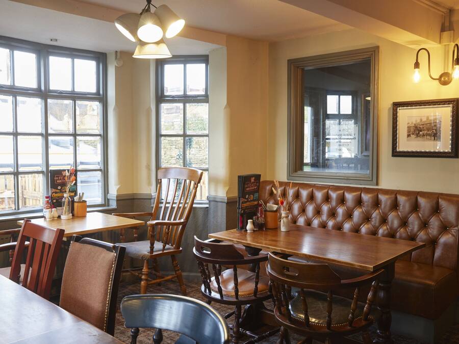 A restaurant interior with wooden tables, leather booths, and large windows.