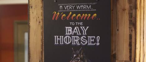A wooden wall with a sign that reads "A VERY WARM Welcome to the BAY HORSE! FROM THE TEAM".