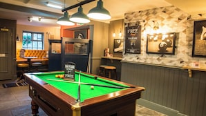 A pool table with balls, a billiard cue, and a sign indicating a free game.