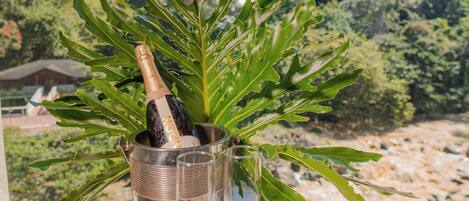 Un tavolo con una bottiglia di champagne e due bicchieri su un balcone affacciato su un paesaggio montano.