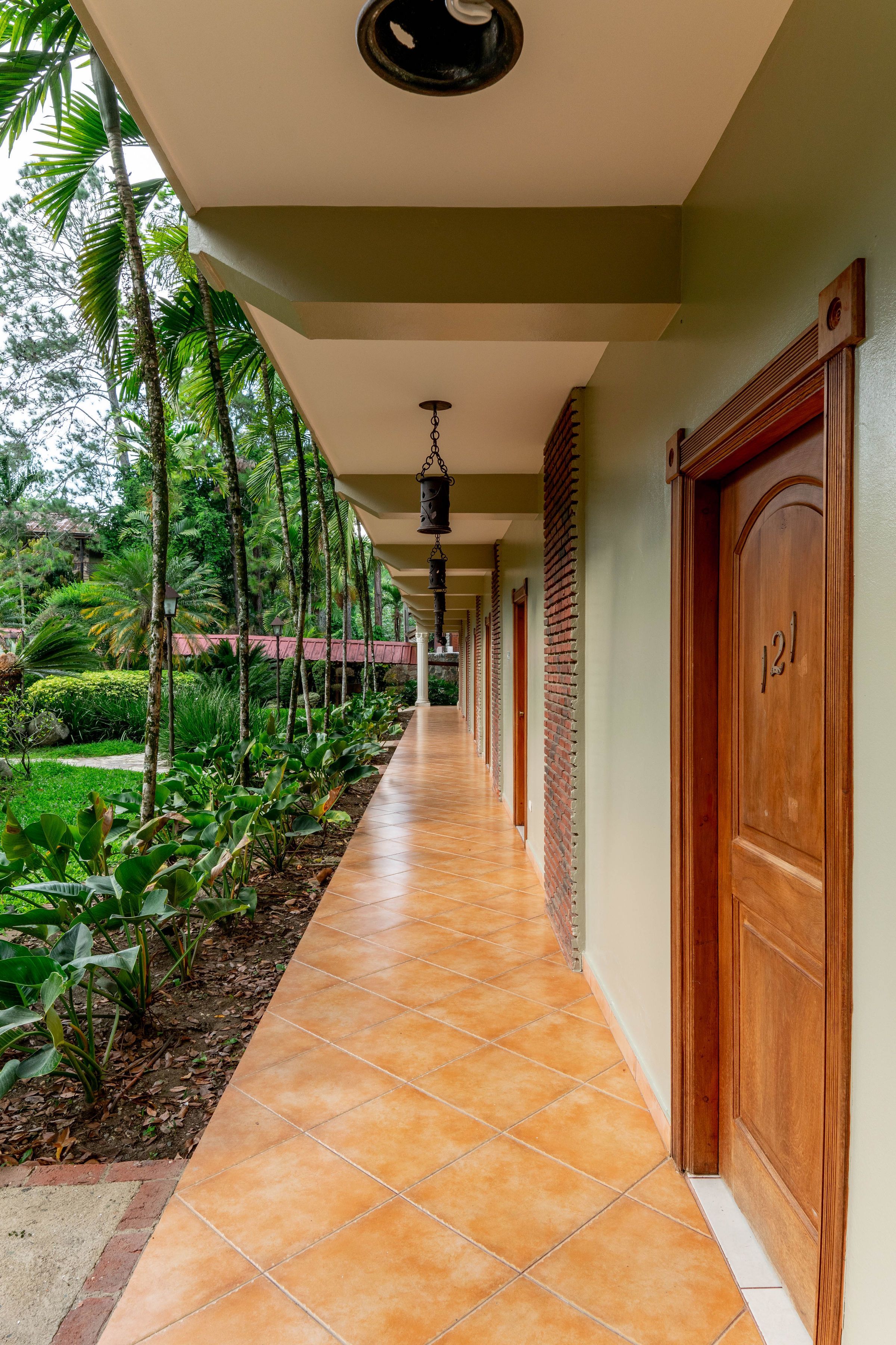 A corridor with tiled flooring, wooden doors, and a hanging light fixture.