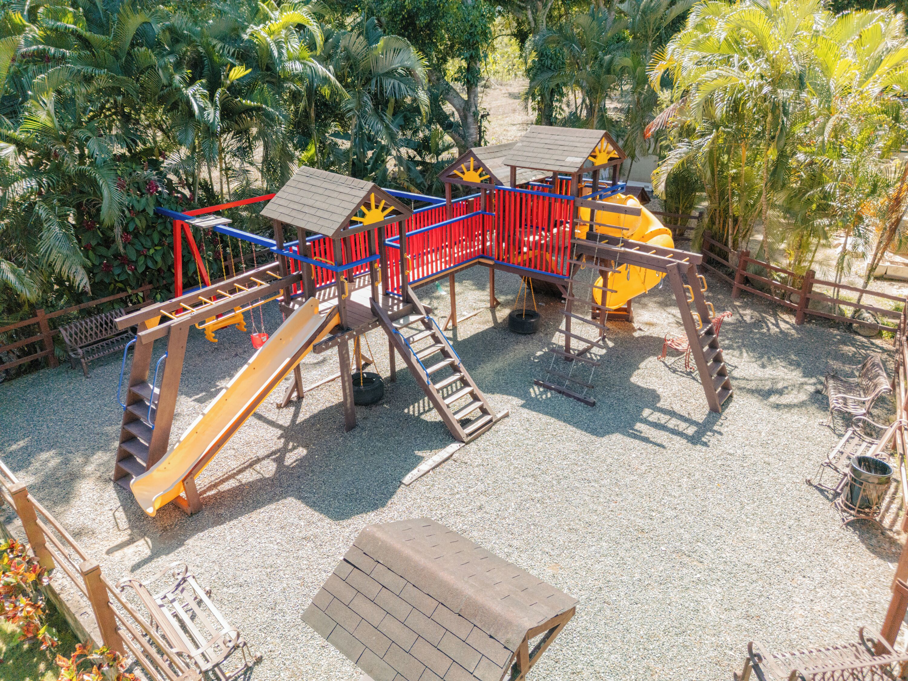 A playground with a slide, climbing structures, and a small house.