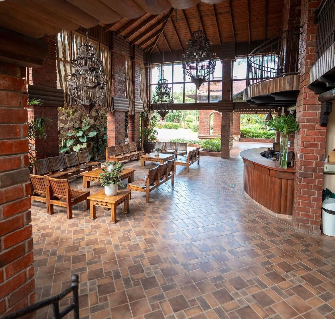 Un vaste espace extérieur aménagé en patio, avec des meubles en bois, des murs en briques et de grandes fenêtres qui laissent entrer la lumière naturelle.
