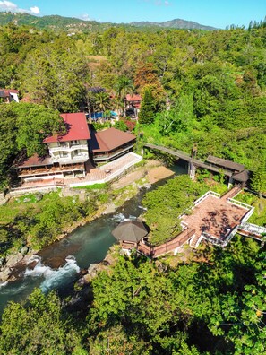 Un resort con un río, un puente y abundante vegetación.