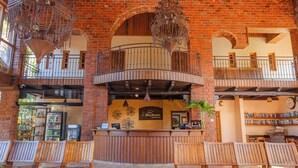 A spacious lobby with a high wooden ceiling, brick walls, and multiple wooden benches. - Hotel Gran Jimenoa (Jarabacoa)