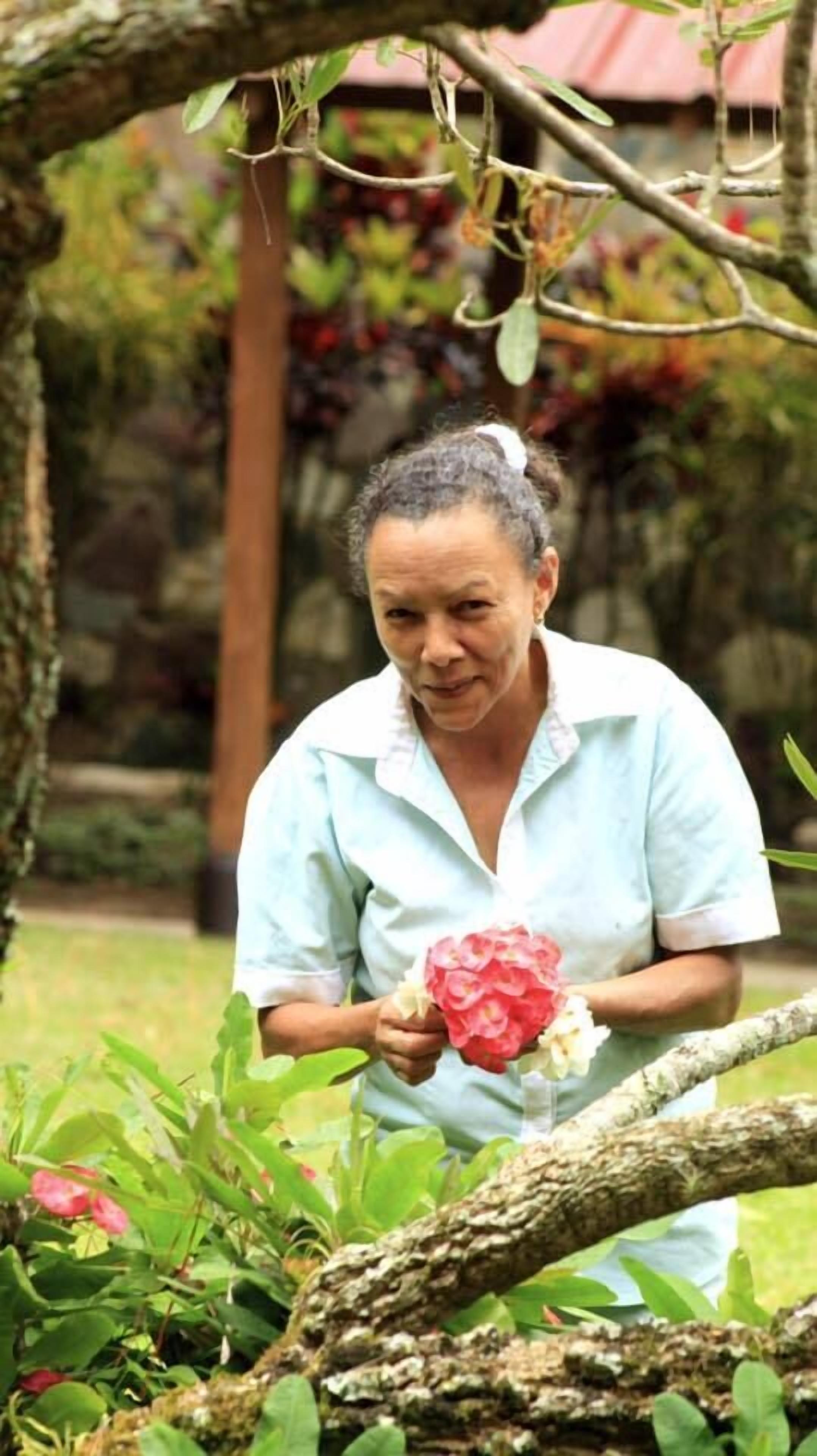 A person holding a bouquet of flowers in a garden setting.
