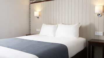 A neatly made bed with white linens and a gray throw blanket, two bedside tables with lamps, and a wall with vertical paneling and butterfly decals.