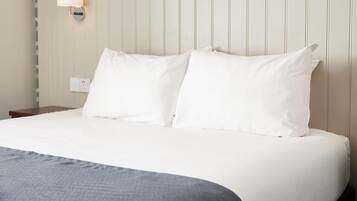 A neatly made bed with white linens and a grey throw blanket.