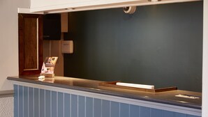 Un mostrador de recepción con paneles azules, una puerta de madera y una cámara de seguridad instalada.