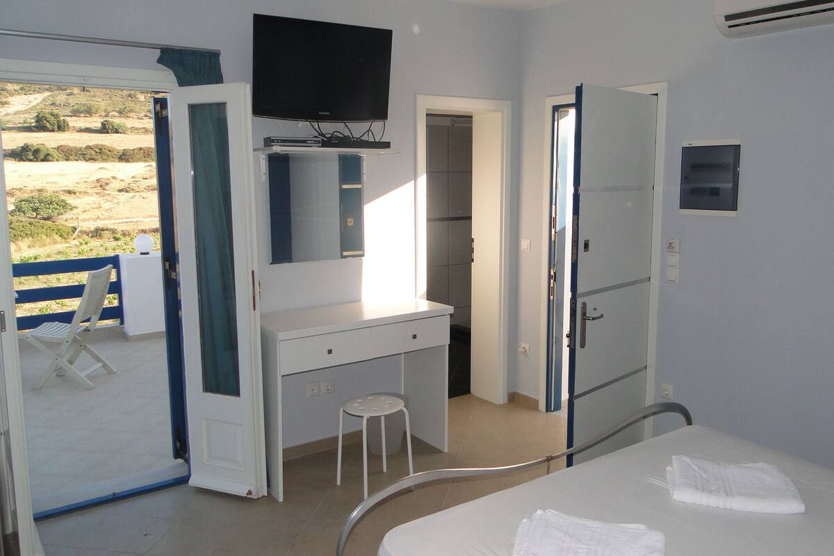 Un dormitorio con cama, escritorio, silla y televisor.