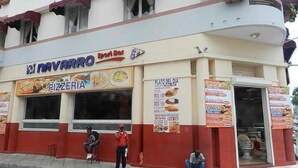 A building with a pizzeria named 'El Navarro' and a sign for 'Plato del Dia' offering various dishes. - Hotel Navarro (Santo Domingo)