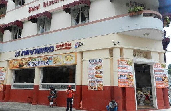 Un edificio con una pizzería llamada 'El Navarro' y un cartel que anuncia el 'Plato del Día' con diversos platos.