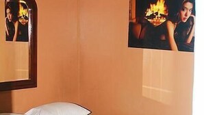 A bedroom with a bed, pillows, a mirror, and two framed pictures on the wall. - Hotel Navarro (Santo Domingo)
