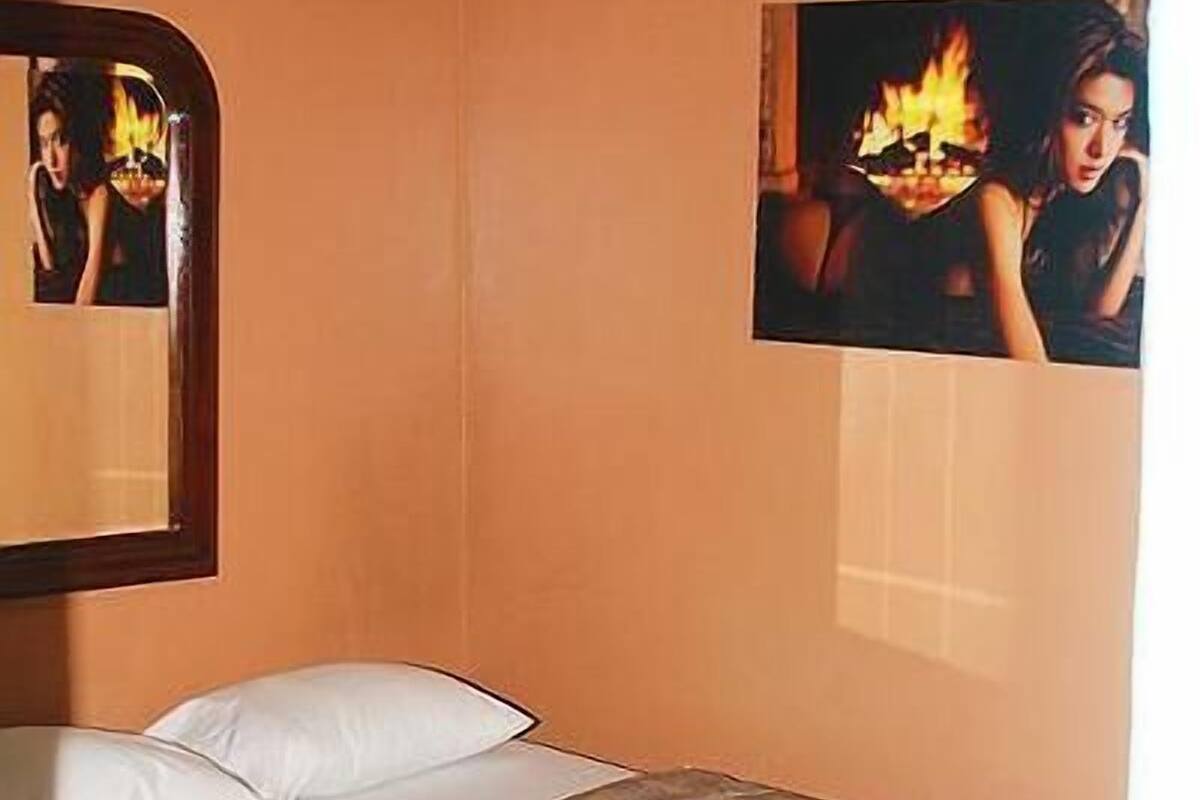 Un dormitorio con cama, almohadas, un espejo y dos cuadros en la pared.