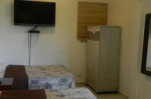 A small room with two beds, a television mounted on the wall, and a wardrobe. - Hotel Navarro (Santo Domingo)