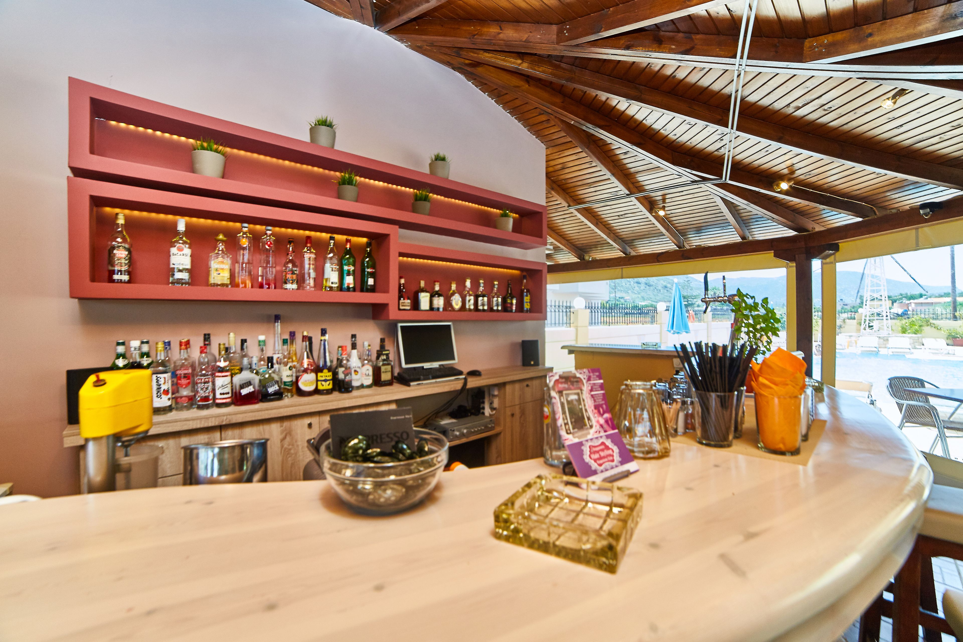 A bar area with shelves of liquor bottles, a cash register, and a bowl of olives.