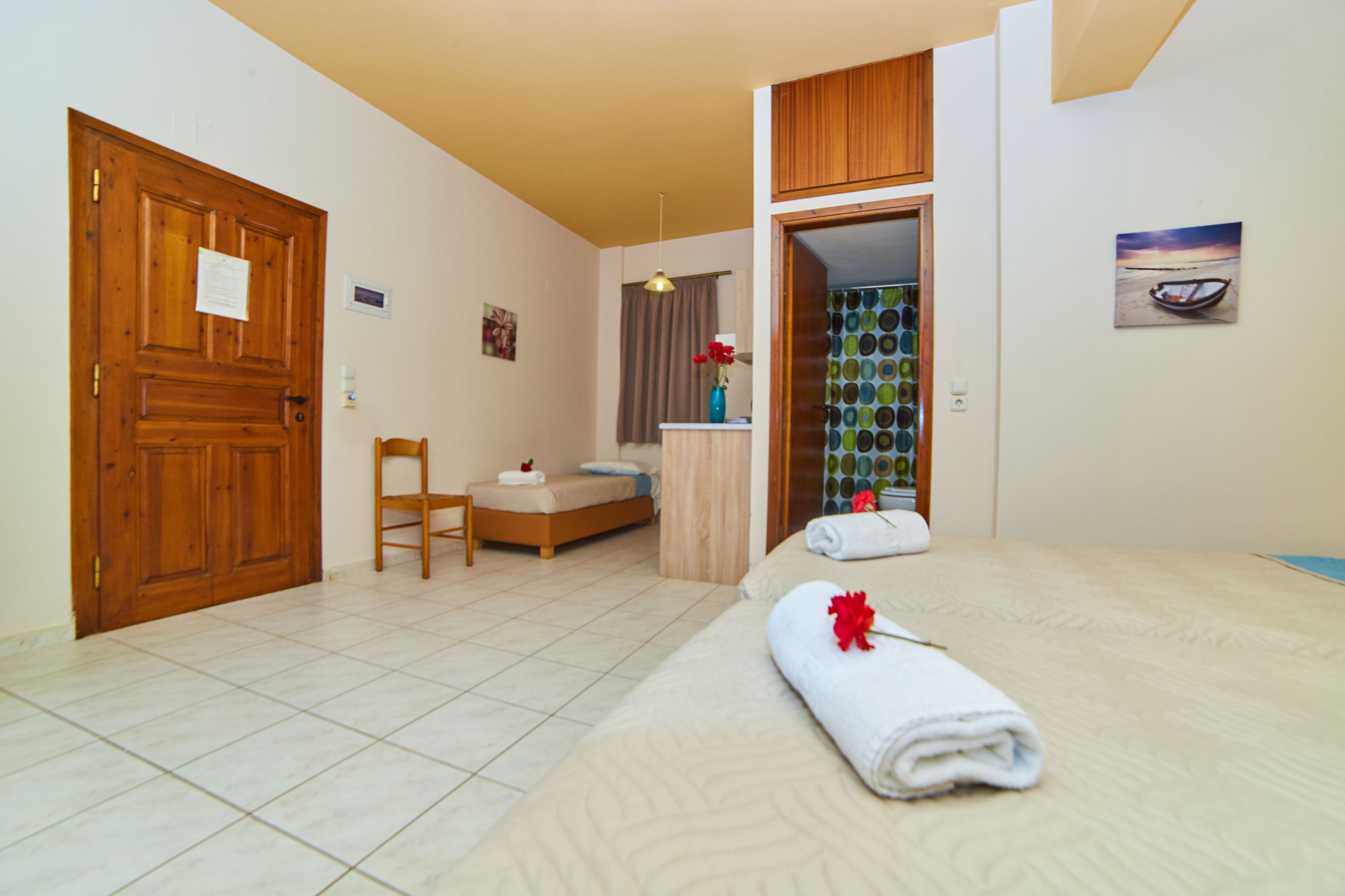 A hotel room with a bed, a chair, a desk, and a bathroom visible through an open door.