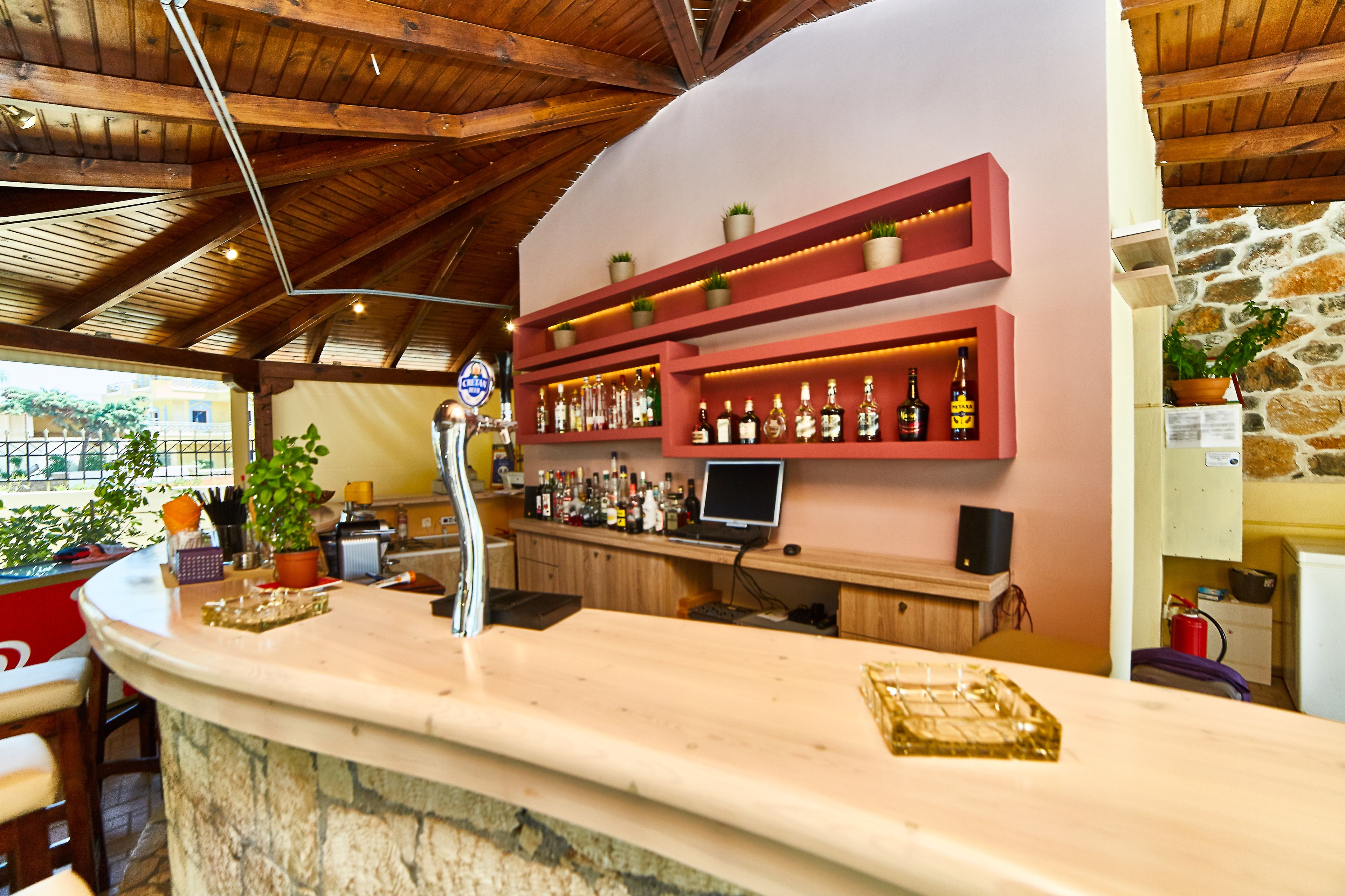 Eine Bar mit Holzbalken, Regalen voller Flaschen und einer Steintheke.