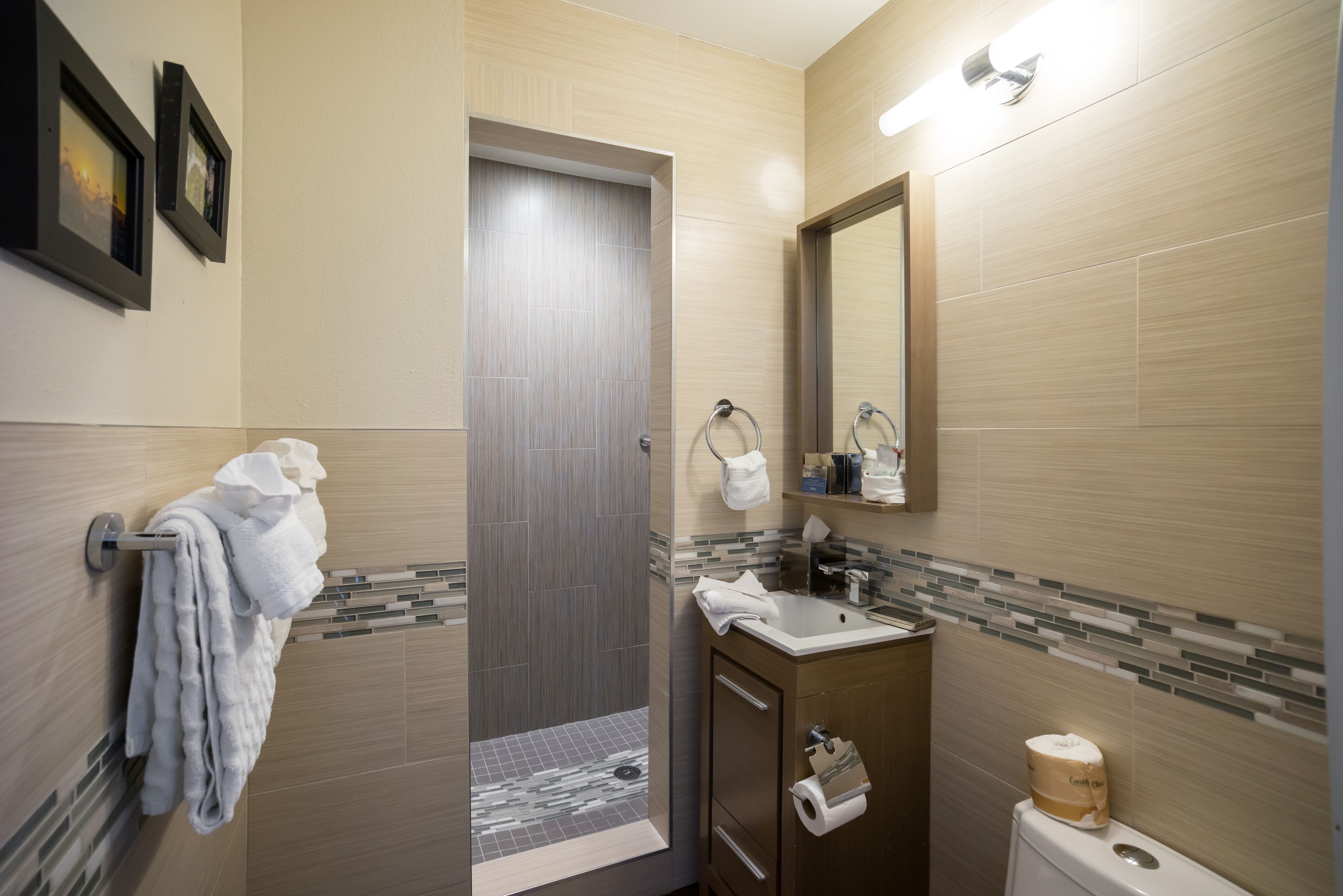 Un bagno moderno con doccia, lavabo e toilette. Asciugamani appesi a un portasciugamani e uno specchio sopra il lavabo.