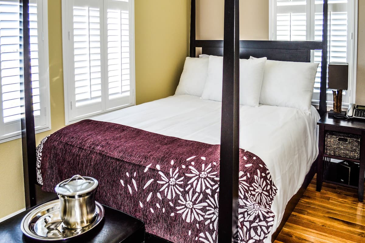 A neatly made bed with white linens, a dark wooden headboard, and a decorative throw blanket.