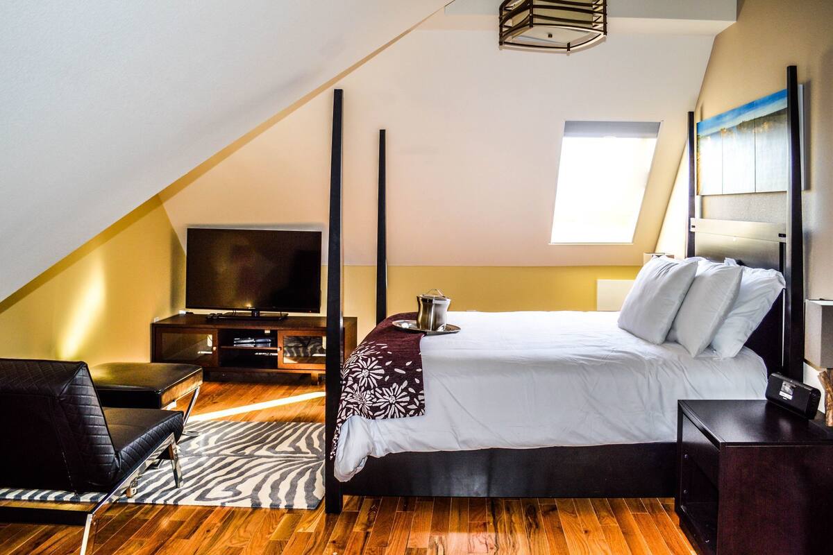 A bedroom with a bed, a TV, a desk, and a chair.