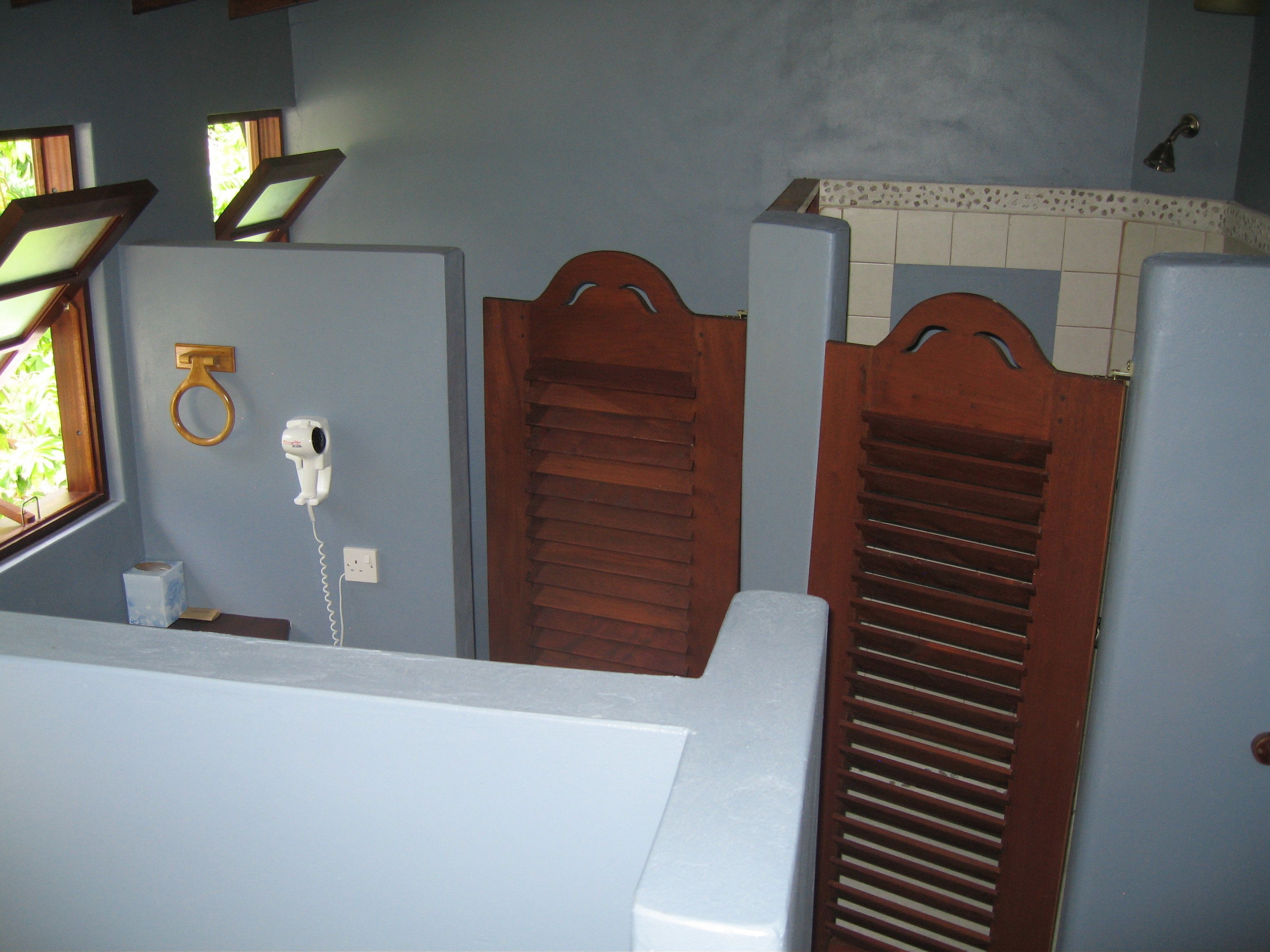 Une salle de bain avec des cloisons en bois, un sèche-mains et un distributeur de serviettes.