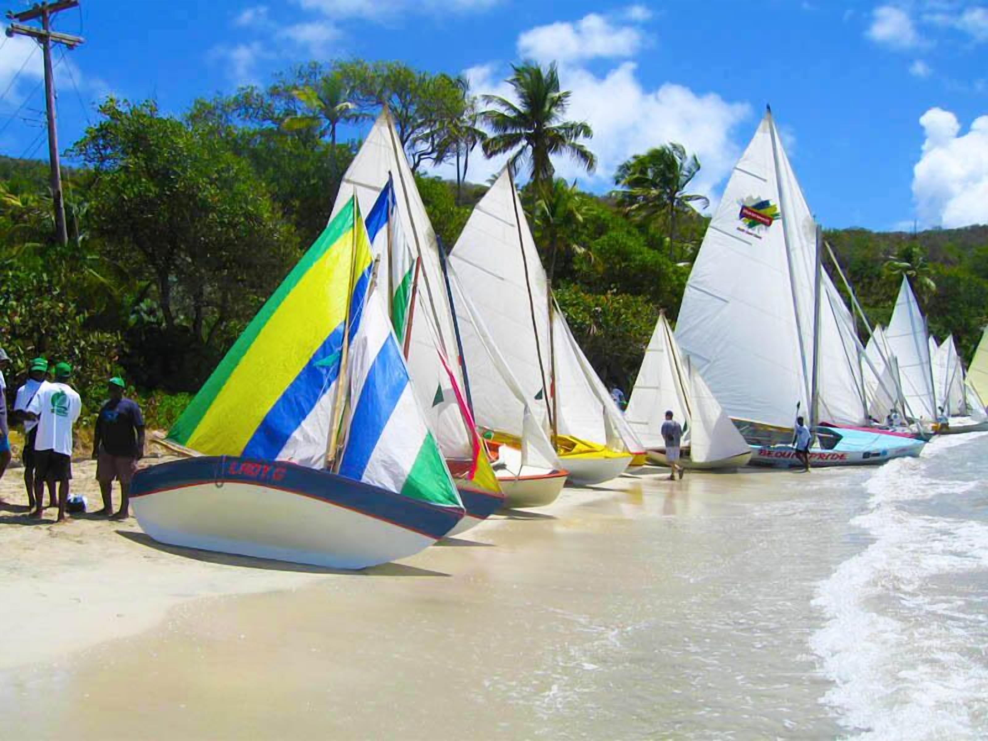 Une plage où plusieurs voiliers sont alignés sur le rivage.