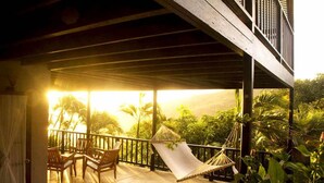 A wooden deck with a hammock and chairs, overlooking lush greenery and a sunset. - Spring Hotel Bequia (Bequia Island)