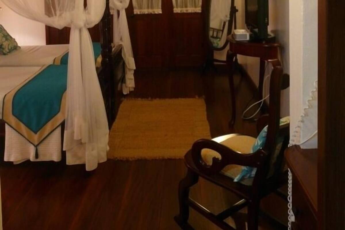 A bedroom with a bed, a chair, a desk, and a mirror.