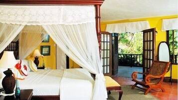 Una habitación con cama con dosel, una silla de madera y un balcón con vistas a zonas verdes.