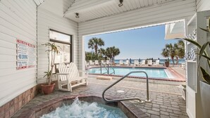 Un espace piscine doté d’un jacuzzi, de chaises longues et offrant une vue sur la plage.