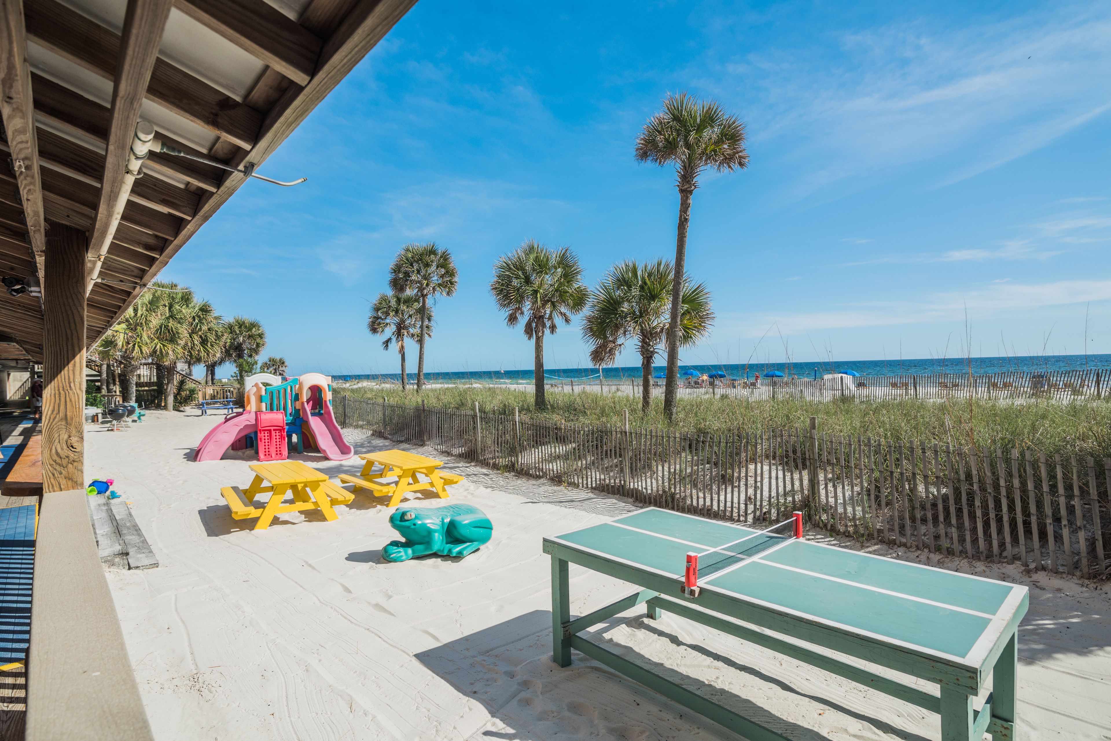 A beachside playground with a slide, tables, and a ping pong table.