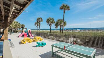 A beachside playground with a slide, tables, and a ping pong table.